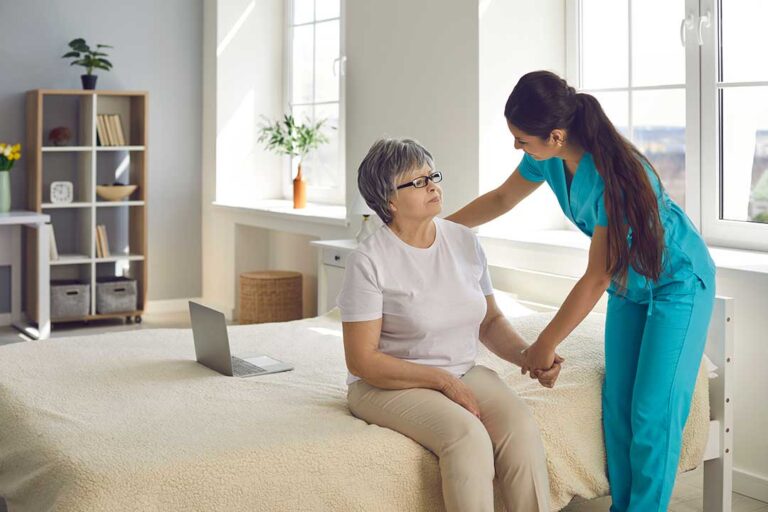 An older adult and a family member sharing a warm moment while unpacking boxes in a sunlit living room.